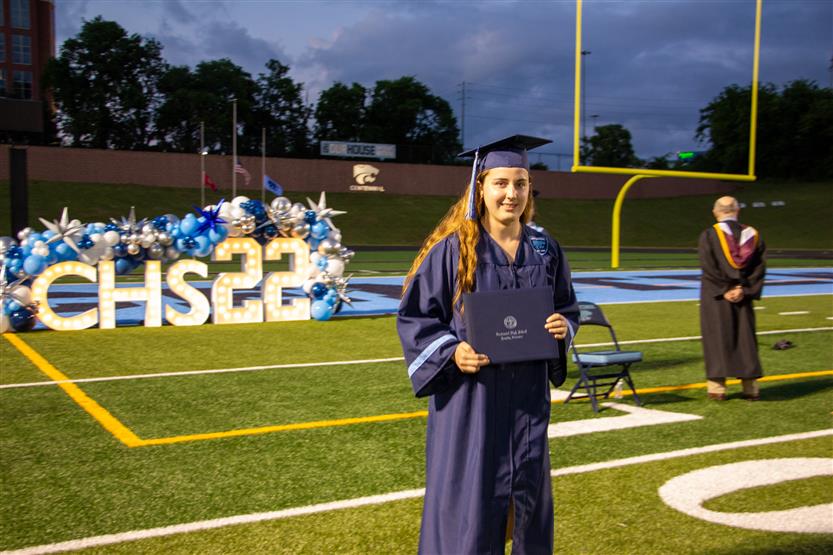 Students graduate outside on a football field